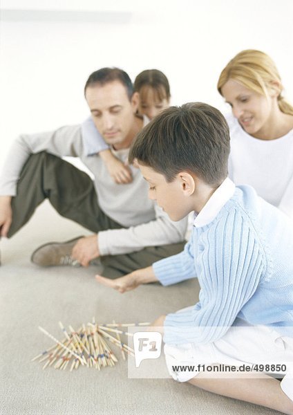 Familienspielende Pick-Up-Sticks auf dem Boden