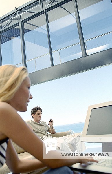 Frau mit Laptop  Mann mit Handy  in der Villa