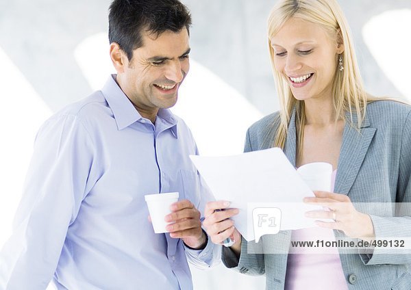 Business associates having coffee and reading document and laughing