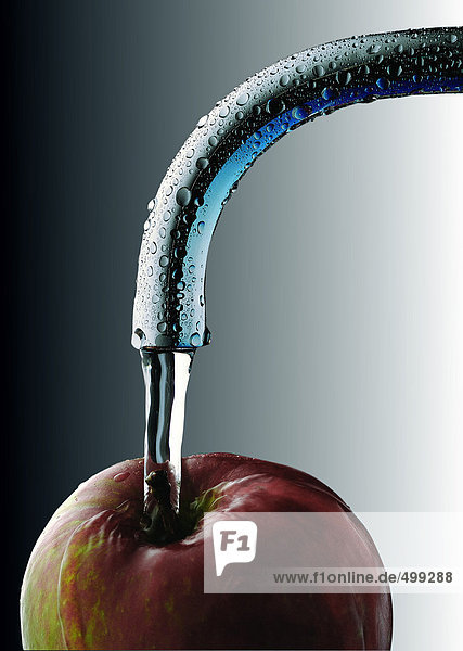 Wasser läuft vom Wasserhahn auf den Apfel  Nahaufnahme
