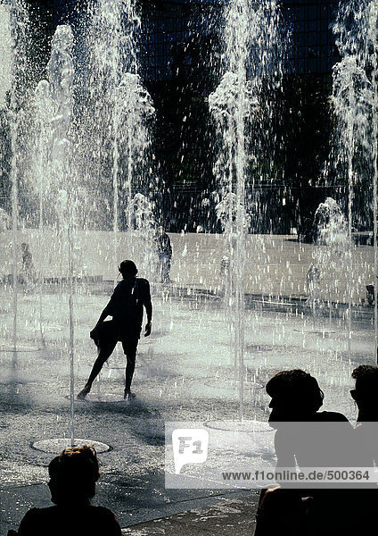 Person silhouetted  standing under fountains
