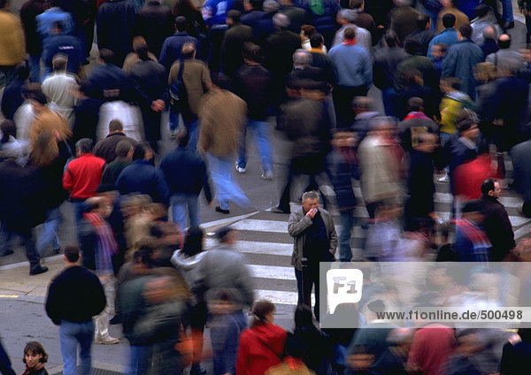 Crowd walking by man standing in opposite direction  blurred motion