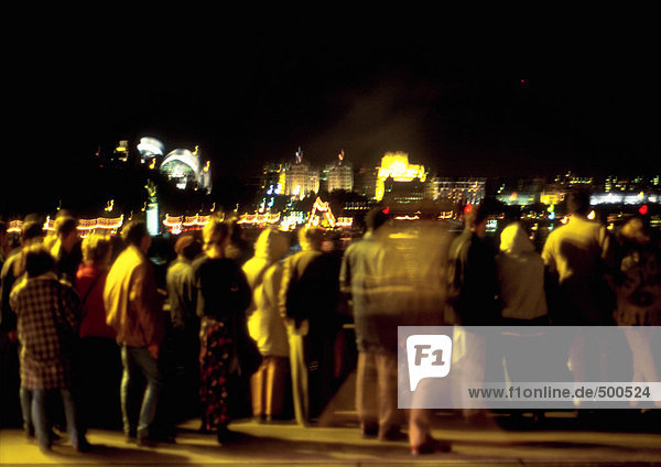 Crowd of people standing at night  rear view  defocused