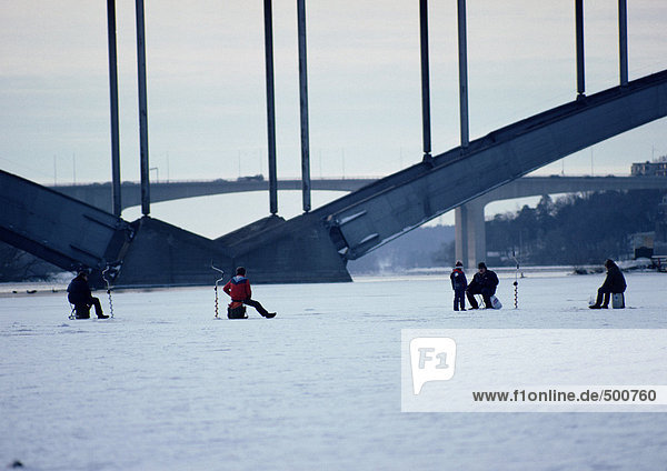 Schweden  Menschen fischen auf dem zugefrorenen Fluss