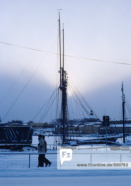 Schweden  Stockholm  zwei Personen am Kai entlang  Bootsmast im Hintergrund