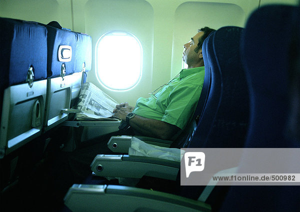Ein Mann  der im Flugzeug schläft.