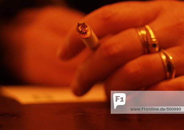 Die Hand der Frau,  die die Zigarette hält,  ganz nah,  verschwommen.