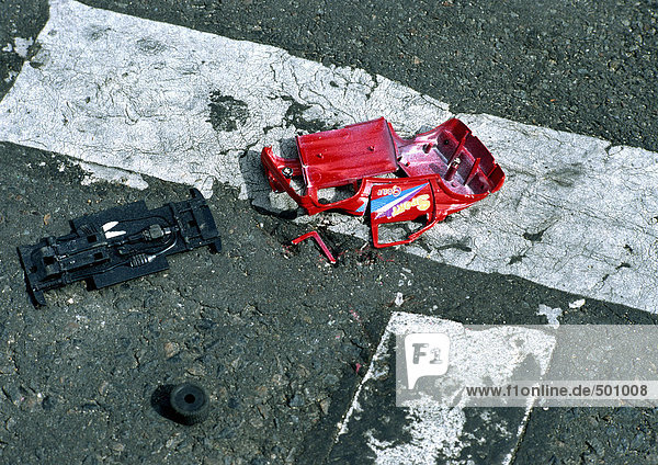 Ein Spielzeugauto ist auf der Straße zertrümmert.