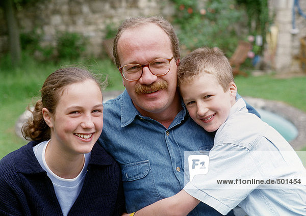 Vater posiert mit Sohn und Tochter draußen,  Porträt.