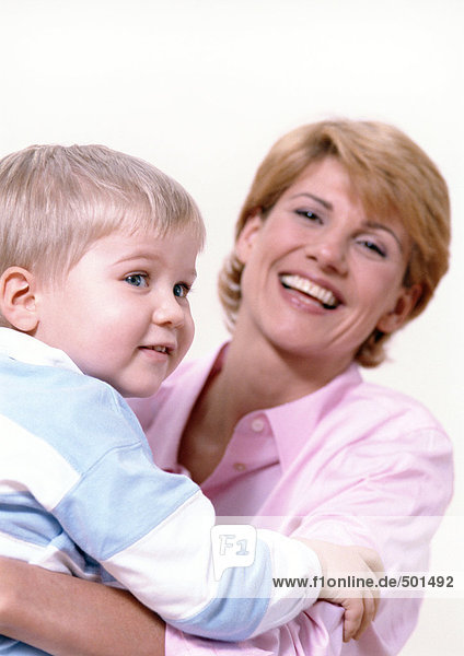 Woman smiling  holding young boy in hands.