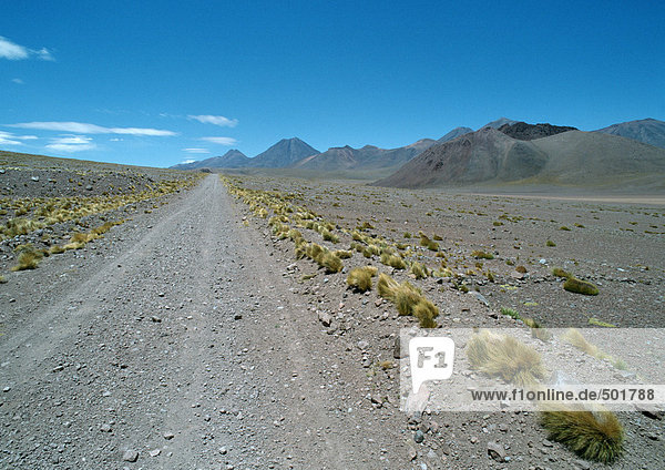 Chile  Antofagasta  Schotterstraße durch trockene Landschaft  Berge im Hintergrund