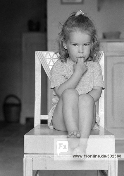 Kleines Mädchen sitzend mit Fingern im Mund  s/w