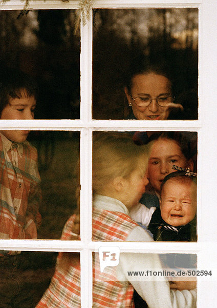 Reife Frau und Kinder hinter dem Fenster