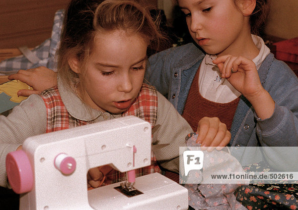 Zwei Mädchen nebeneinander  eines mit Nähmaschine