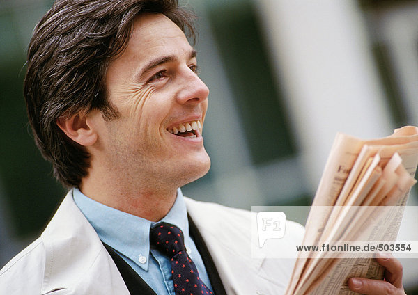 Businessman holding newspaper  smiling  portrait