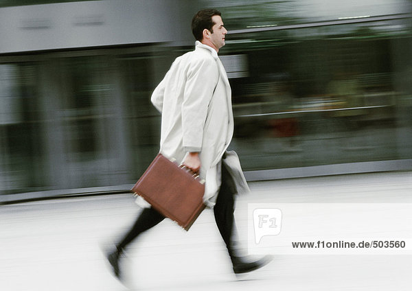 Businessman holding briefcase  running  blurred