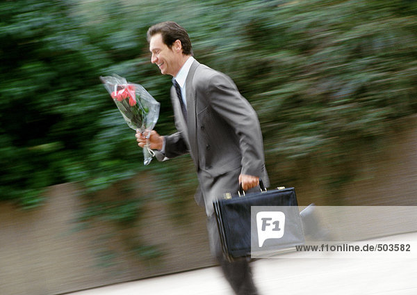 Geschäftsmann mit Aktentasche und Blumenstrauß  rennend  verschwommen