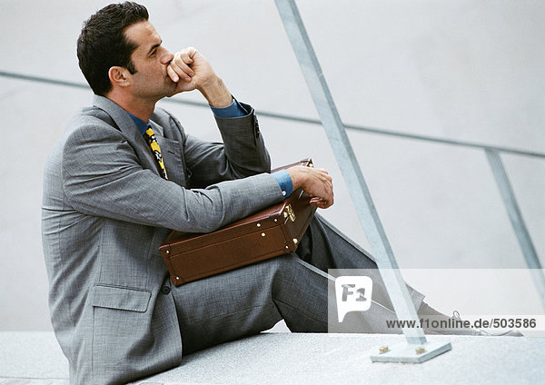 Businessman sitting on stairs  holding briefcase