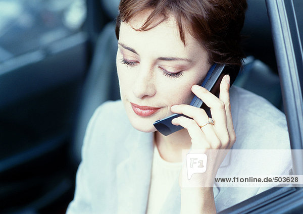 Businesswoman sitting in car looking down  using cell phone