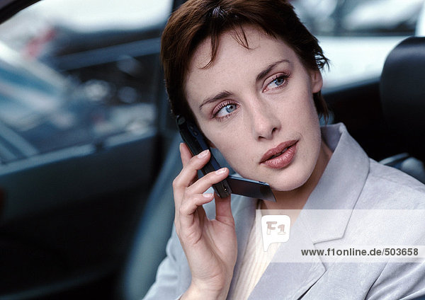Geschäftsfrau im Auto mit dem Handy  wegschauen  Portrait