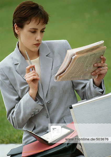 Geschäftsfrau sitzend  Zeitung anschauend