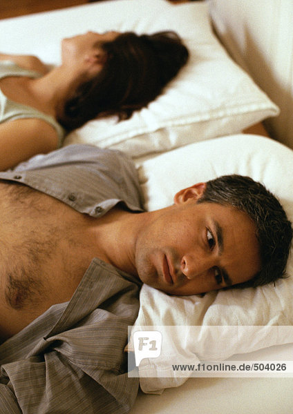 Mann und Frau liegen im Bett  Köpfe auf Kissen  gegensinnig  Kopf und Schultern