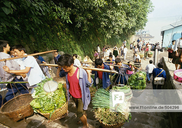 China  Sichuan  Chongqing  workers carrying yoked baskets of produce up steps leading from river boat dock
