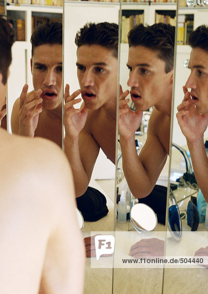 Mann berührt die Lippen  reflektiert in Spiegeln