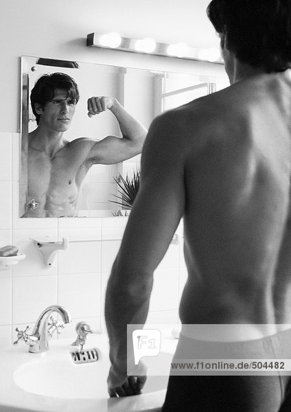 Mann beugt Armmuskeln vor dem Spiegel  s/w