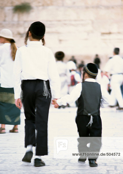 Israel  Jerusalem  two Orthodox Jewish boys wearing kippas and holding hands  rear view