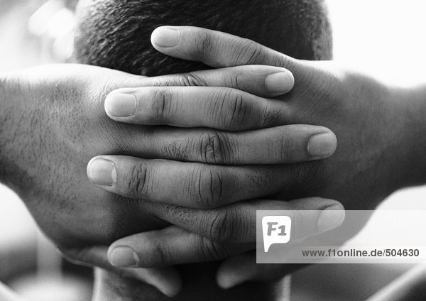 Man's hands clasped behind head  close-up  b&w