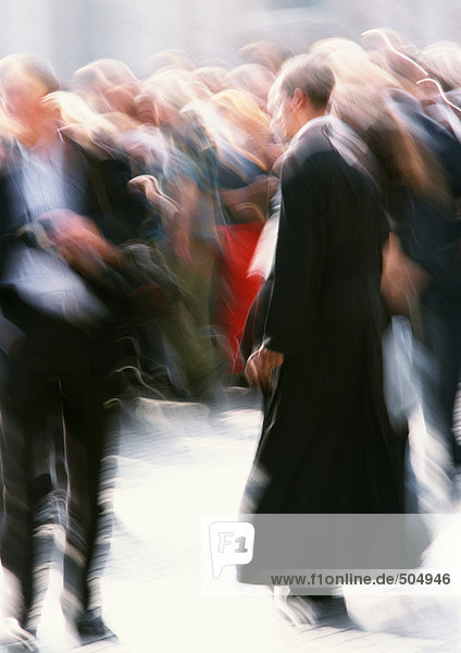 Priest walking in crowd outside  blurred