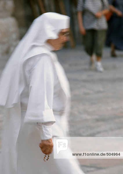 Nun walking in street  side view