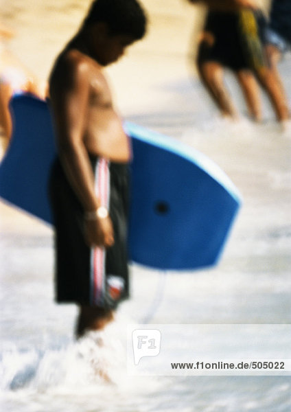 Person holding bodyboard  feet in water  blurred