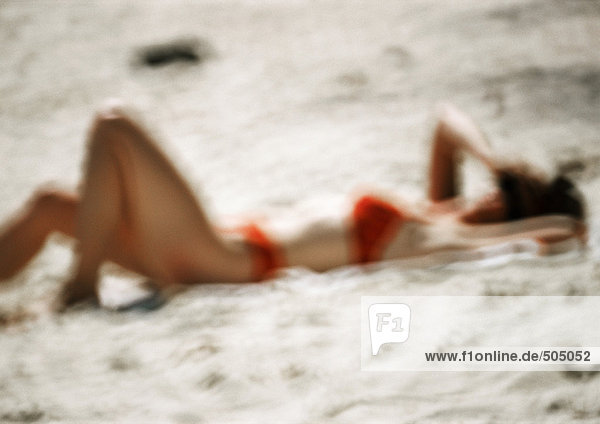 Woman in swimming suit  lying on sand  blurred