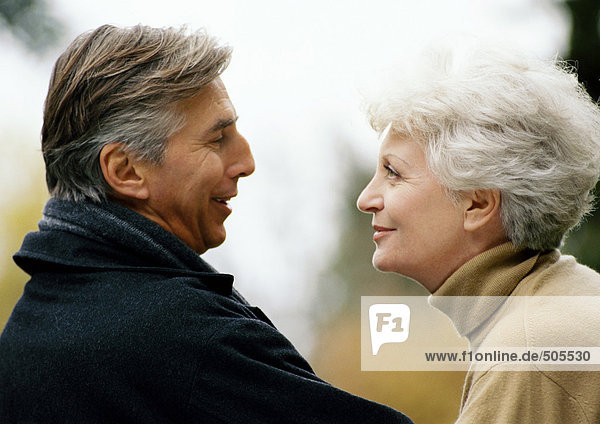 Man and woman facing each other  smiling  head and shoulders  close-up