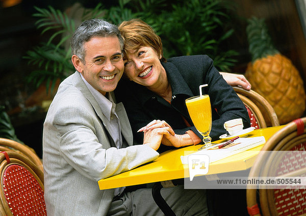 Mann und Frau sitzen am Tisch und lehnen sich eng aneinander  Portrait