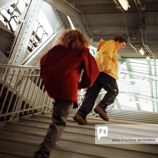Junge Leute  die in einer erhöhten U-Bahn-Station die Treppe hinaufgehen.