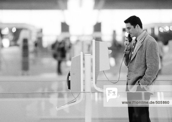 Geschäftsmann mit Münztelefon im Terminal  schwarz-weiß.