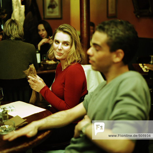 Junger Mann und Frau sitzen am Tisch im Café  Frauen schauen den Mann an.