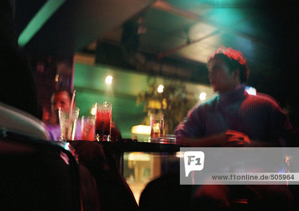Junger Mann in der Bar sitzend  zweite Person im Hintergrund  Blickwinkel niedrig
