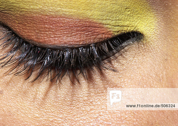Geschlossenes Auge der Frau mit gelbem und orangem Lidschatten  extreme Nahaufnahme