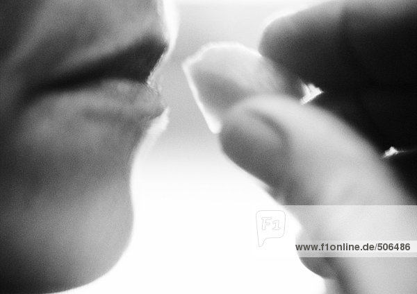Nahaufnahme der Hand  die das Essen in den Mund der Frau bringt  schwarz-weiß  Seitenansicht