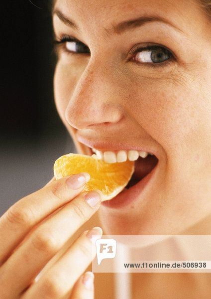 Woman eating orange slice  close-up