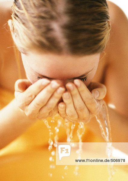 Frau lehnt sich nach vorne  schröpft Wasser ins Gesicht  Nahaufnahme