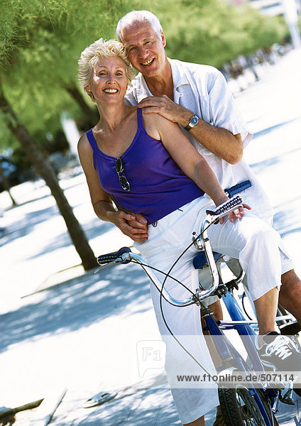 Mature man and woman posing on stationary bike  portrait