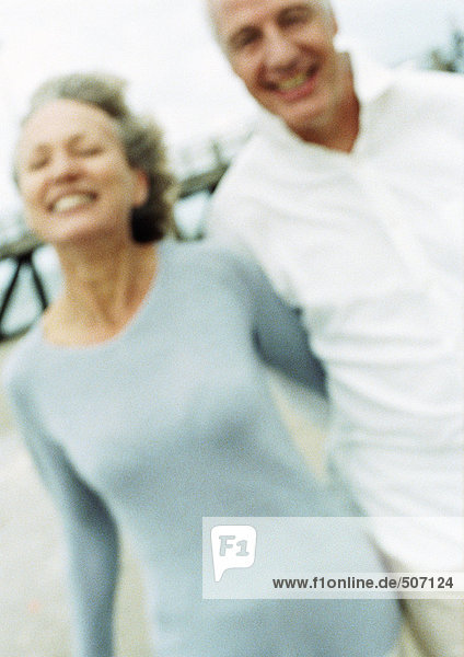 Mature couple smiling on beach  blurred portrait