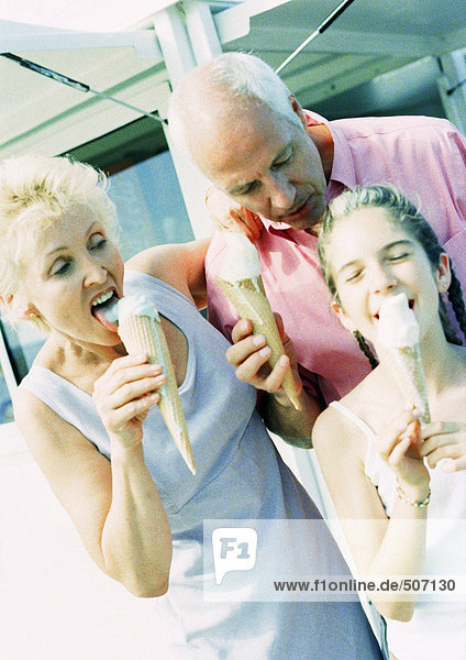 Ein reifes Paar und ein junges Mädchen essen Eistüten draußen.