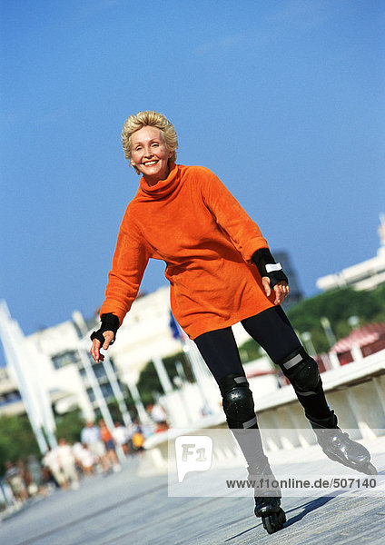 Reife Frau beim Inline-Skaten auf der Promenade
