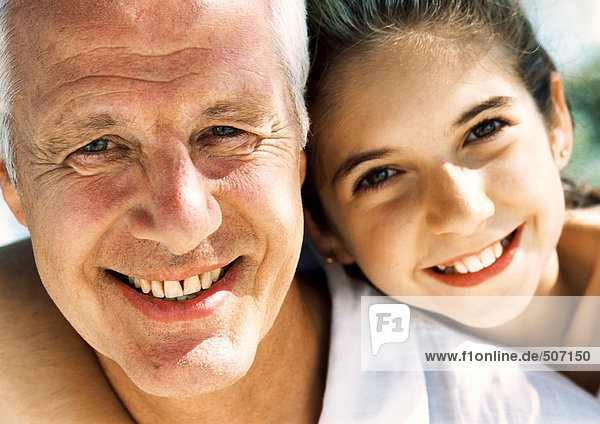 Mature man and girl smiling  close up  portrait